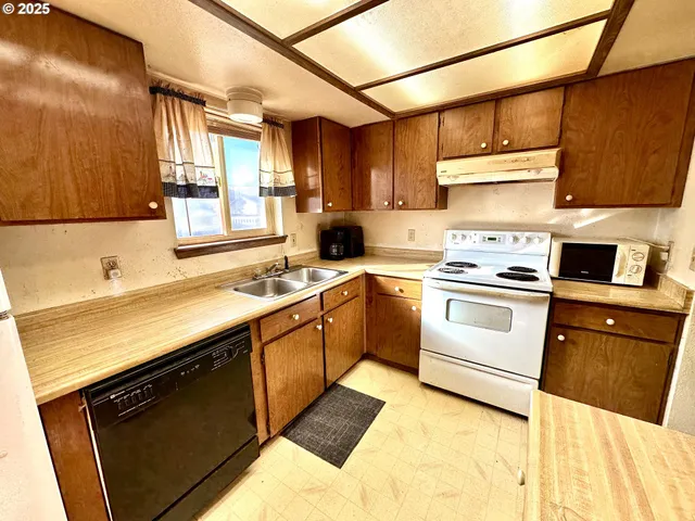 a kitchen with granite countertop a sink stainless steel appliances wooden floor and cabinets