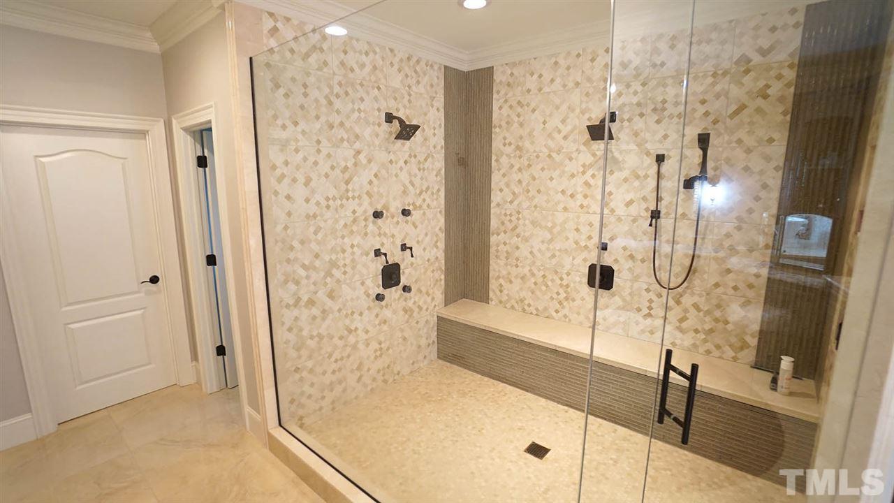 1608 Sharnbrook Court Raleigh, NC 27614 - Photo 17 of 30 Oversized, walk-in frameless shower for 2 w/tumbled tile flooring & matching tile surround, double shower heads, hand held sprayer, & built-in bench w/tile wall