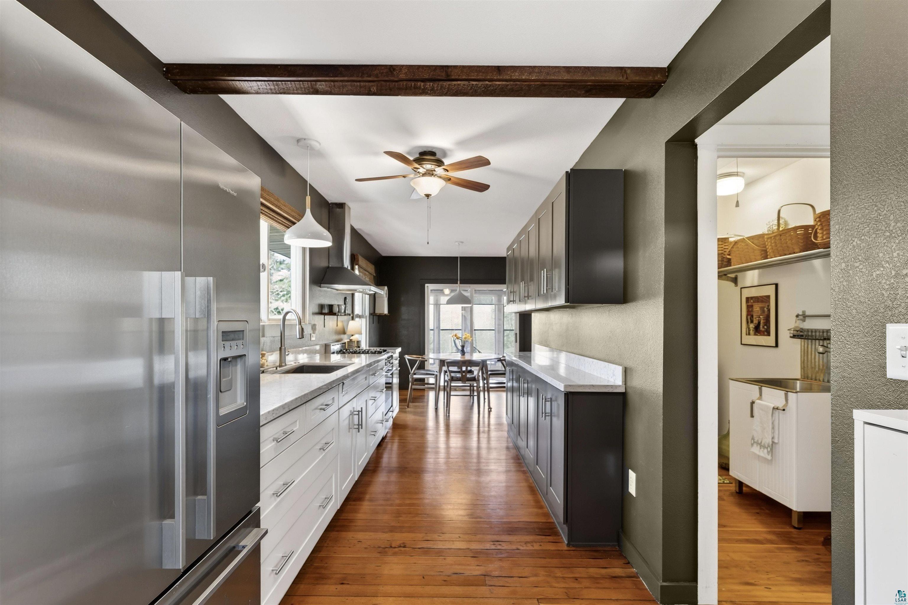 13885 Park Road Brule, WI 54820 - Photo 2 of 41 Gourmet kitchen featuring stainless steel appliances, white perimeter cabinetry, dark wood-finish upper and lower cabinetry, light-toned countertops, and wood-finish flooring