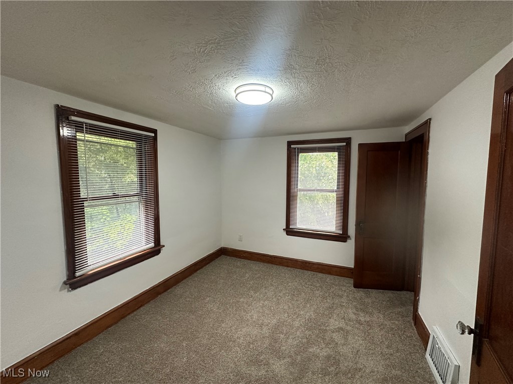 835 Inman Street Akron, OH 44306 - Photo 19 of 25 Unfurnished bedroom featuring carpet, multiple windows, and a textured ceiling
