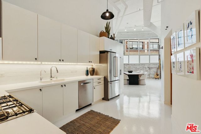 a living room with stainless steel appliances furniture a fireplace and a window