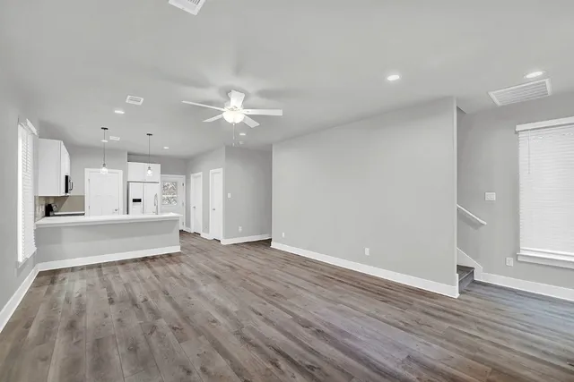 a view of an empty room and window wooden floor and a kitchen