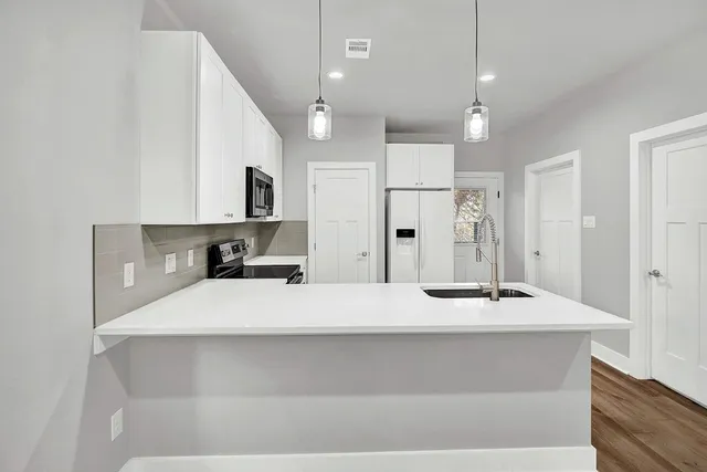 a large white kitchen with kitchen island stainless steel appliances sink and cabinets