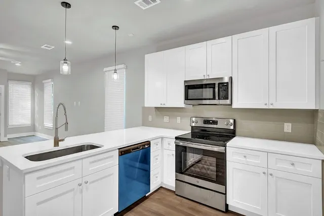 a kitchen with granite countertop white cabinets white stainless steel appliances and a sink