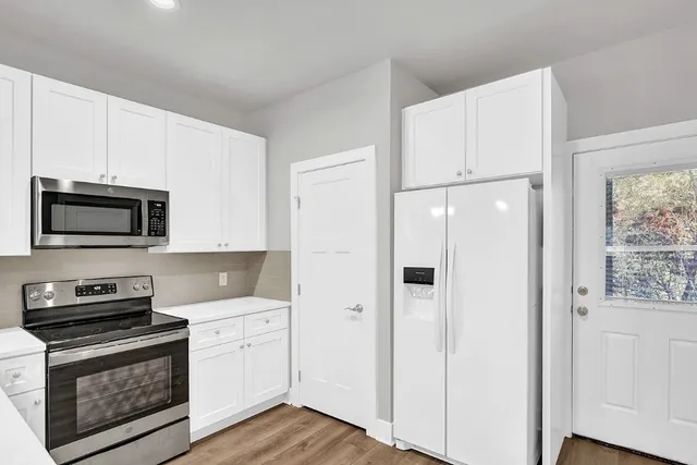 a kitchen with stainless steel appliances white cabinets and wooden floors
