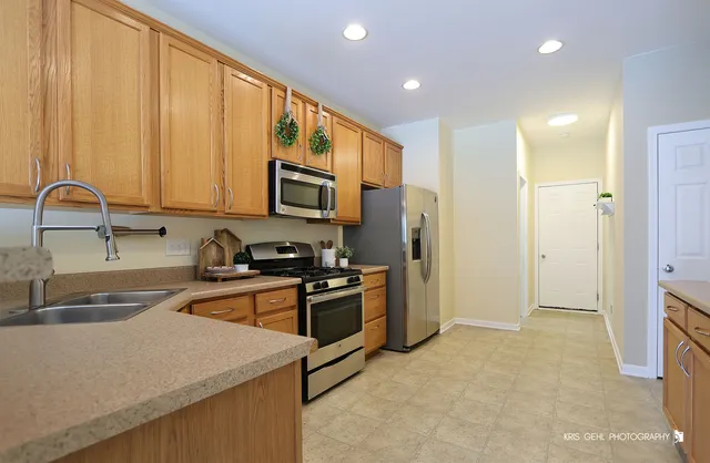 a kitchen with stainless steel appliances granite countertop a stove a sink and a refrigerator with wooden floor