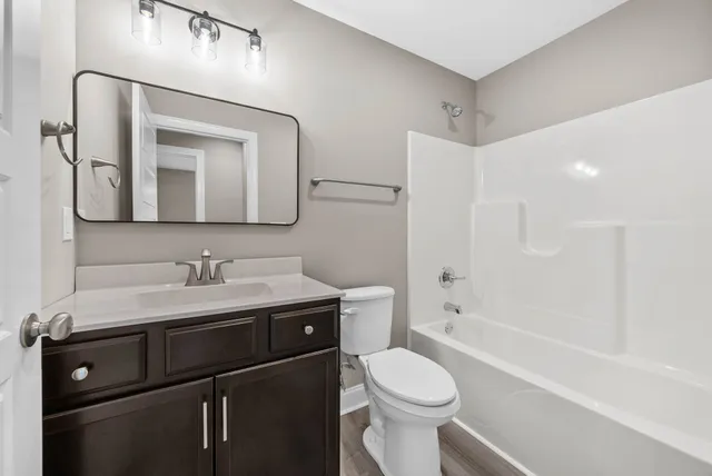 a bathroom with a toilet a sink a tub and mirror