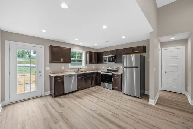 a large kitchen with stainless steel appliances kitchen island granite countertop a refrigerator and a stove top oven