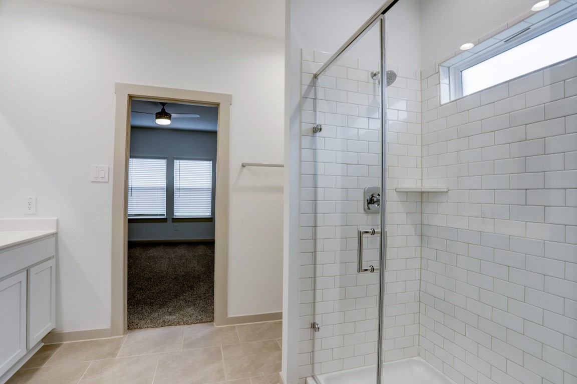 29866 Wildcat Way Katy, TX 77494 - Photo 15 of 25 Another view of the beautifully designed primary bathroom highlighting the large glass-enclosed walk-in shower with classic white subway tile and built-in shelf for convenience. A window above the shower allows natural light to brighten the space while maintaining privacy. The clean modern finishes and neutral palette create a spa-like environment that feels fresh, bright, and thoughtfully designed for everyday comfort.