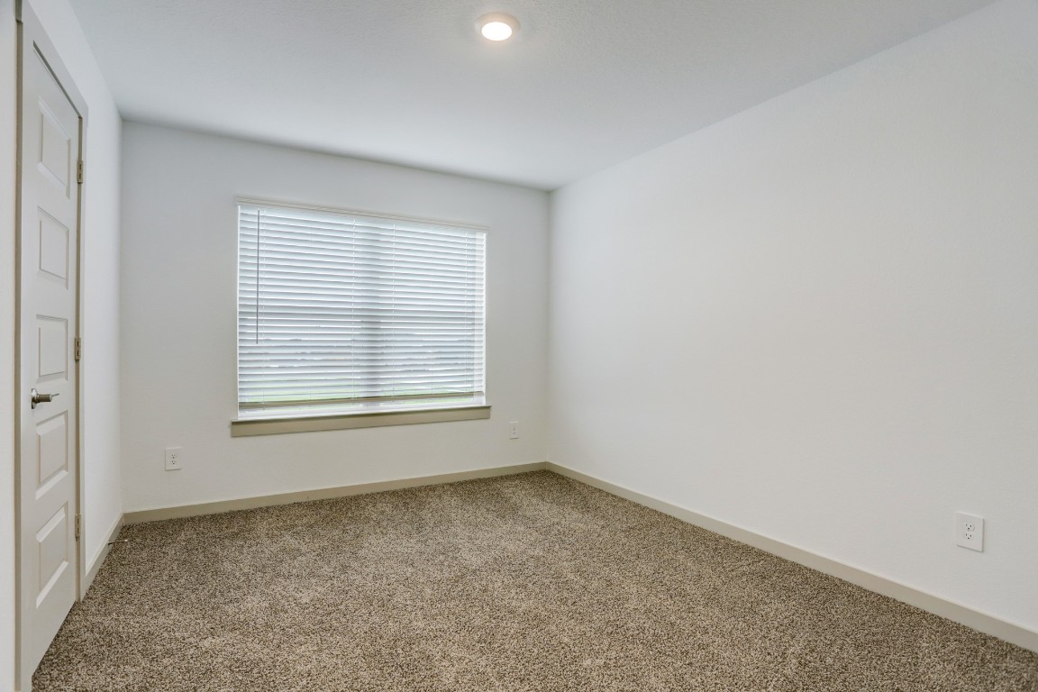 29866 Wildcat Way Katy, TX 77494 - Photo 20 of 25 Another spacious bedroom offering plush carpeting, neutral walls, and a wide window that fills the space with natural light. The room’s simple and functional layout allows for flexible furniture arrangements while maintaining a cozy and relaxing environment. Perfect for guests, family members, or a home workspace, this room continues the clean, modern aesthetic found throughout the home.