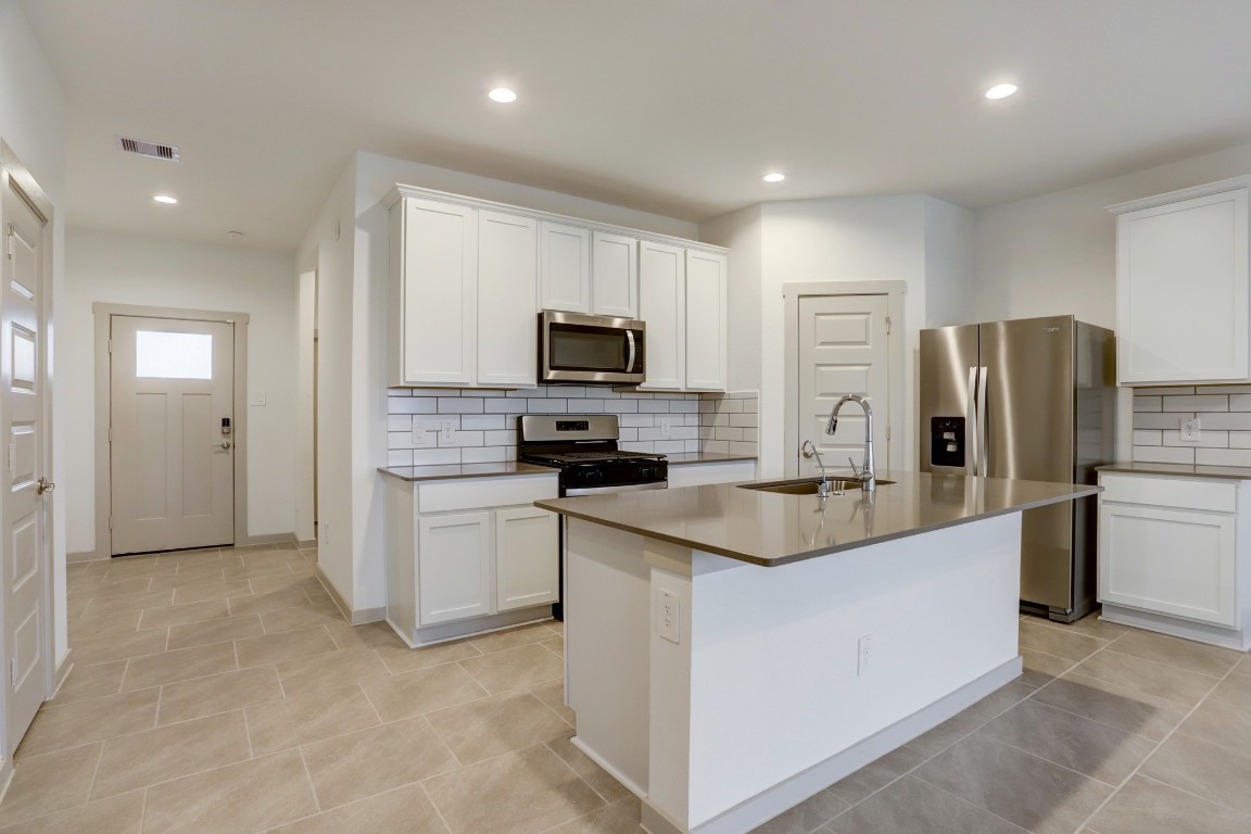 29866 Wildcat Way Katy, TX 77494 - Photo 6 of 25 Beautifully designed kitchen with a large center island that serves as the heart of the home. The crisp white cabinetry contrasts elegantly with the stainless steel appliances and neutral countertops, creating a clean, modern aesthetic. The island offers additional prep space and seating, making it ideal for casual meals or entertaining guests. The open layout ensures the kitchen remains connected to the main living areas for a seamless flow.