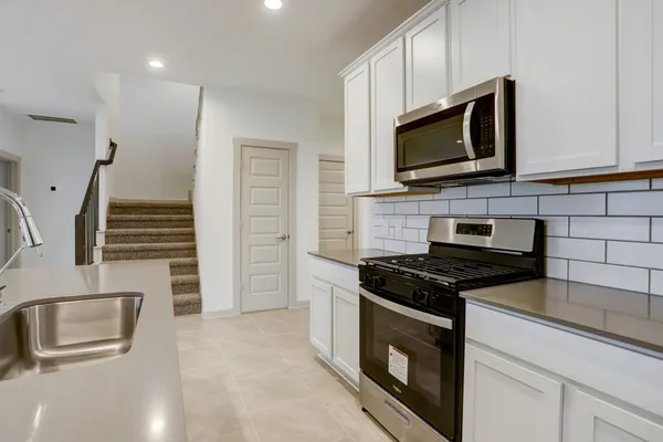 a kitchen with granite countertop a stove and a microwave