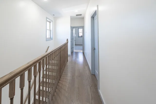 a view of a hallway with wooden floor and a bathroom