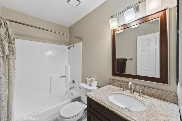 a bathroom with a granite countertop sink toilet a mirror a vanity and shower