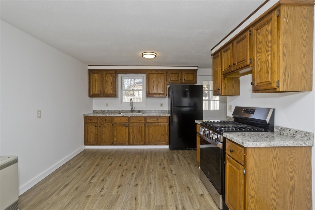 53 Champlain Street Springfield, MA 01151 - Photo 5 of 30 a kitchen with stainless steel appliances granite countertop a stove a sink dishwasher a refrigerator and a microwave oven with wooden floor