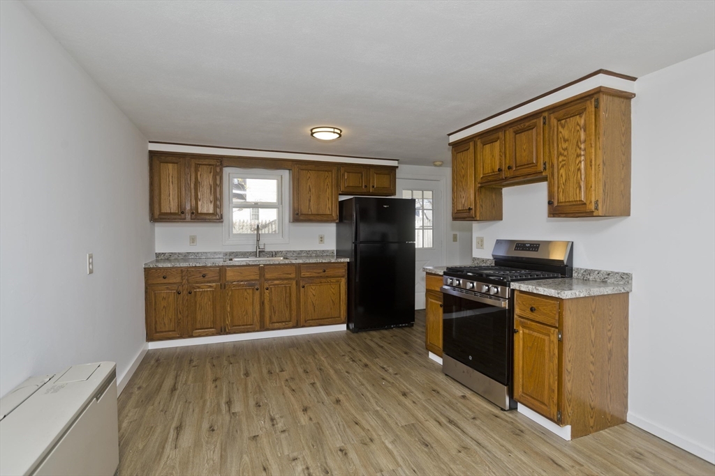 53 Champlain Street Springfield, MA 01151 - Photo 6 of 30 a kitchen with granite countertop wooden floors stainless steel appliances a sink and a window