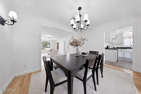 a kitchen with stainless steel appliances granite countertop a sink a stove a dining table and chairs with wooden floor