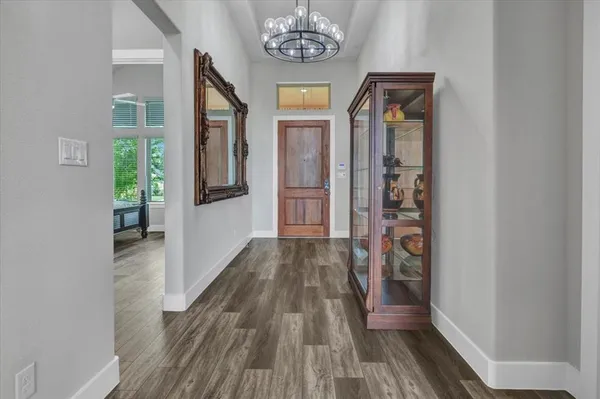 a view of hallway with wooden floor and chandelier