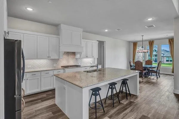 a kitchen with stainless steel appliances granite countertop a table chairs sink refrigerator and cabinets