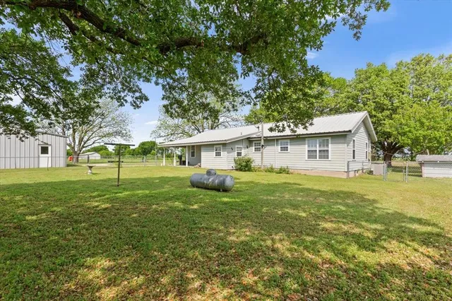 a view of a house with a big yard and large trees