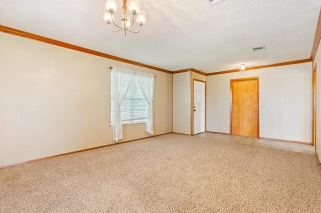 an empty room with chandelier fan and windows