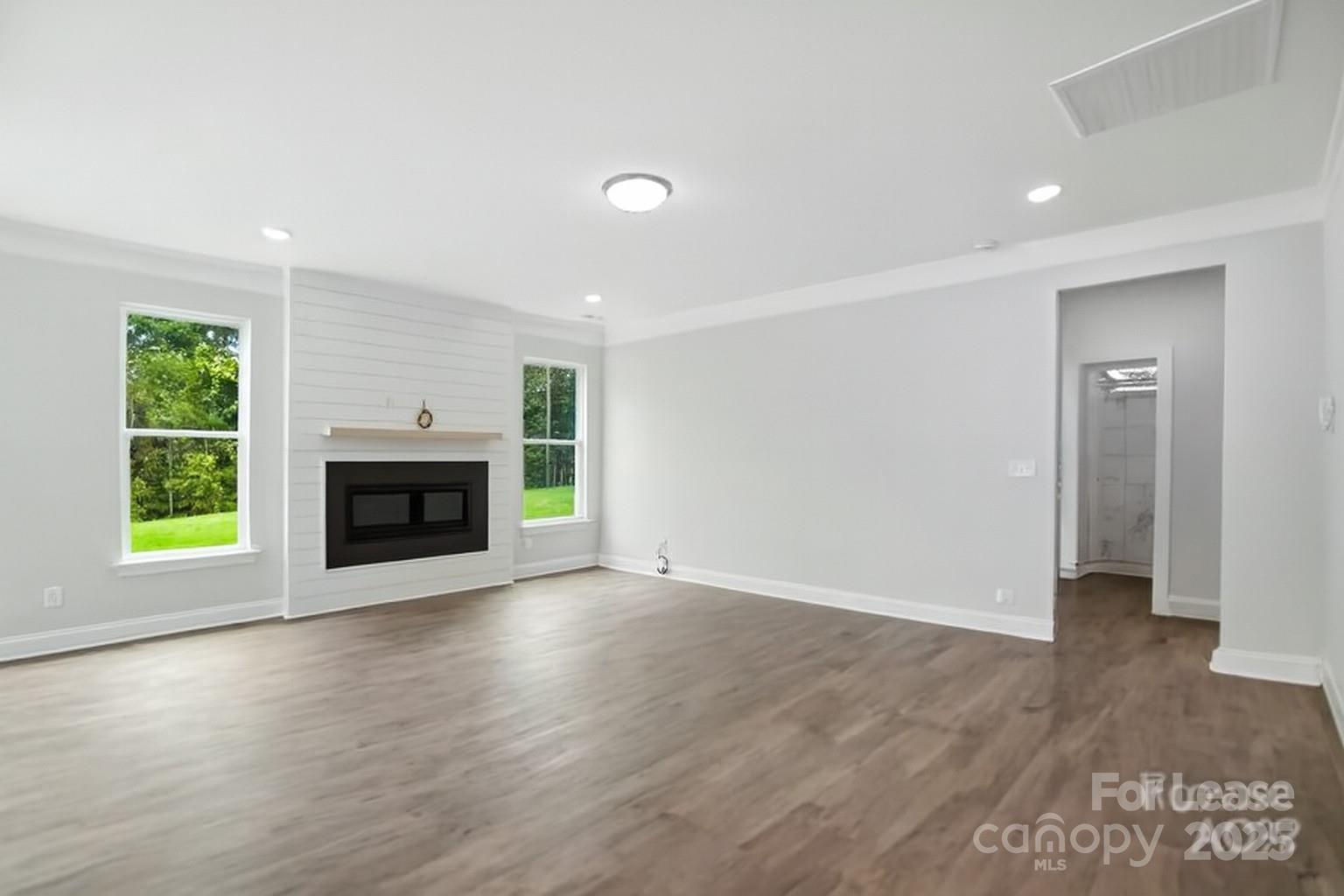 5409 Verona Road Charlotte, NC 28213 - Photo 7 of 20 an empty room with wooden floor a fireplace and windows
