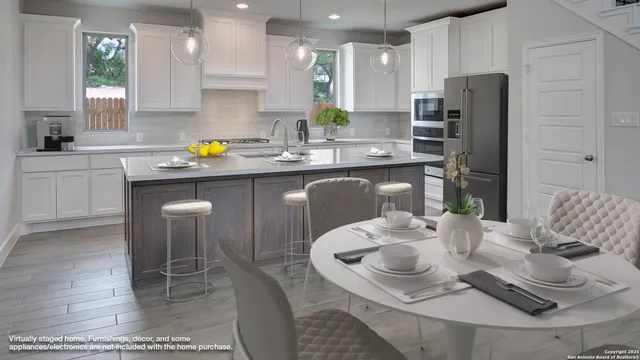 a kitchen with stainless steel appliances kitchen island granite countertop a table chairs and a refrigerator