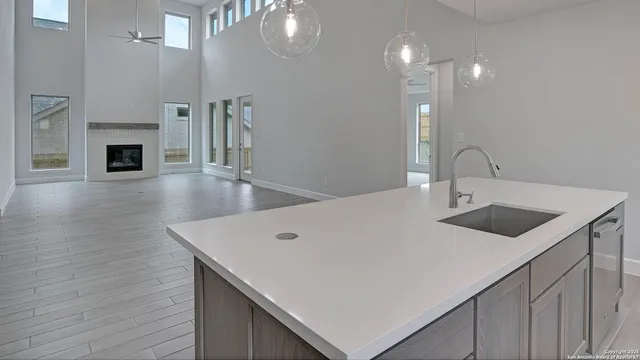 a kitchen with stainless steel appliances a sink a microwave a stove and white cabinets with wooden floor