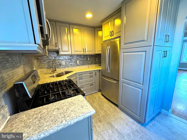 a kitchen with stainless steel appliances granite countertop a refrigerator a sink dishwasher and wooden cabinets