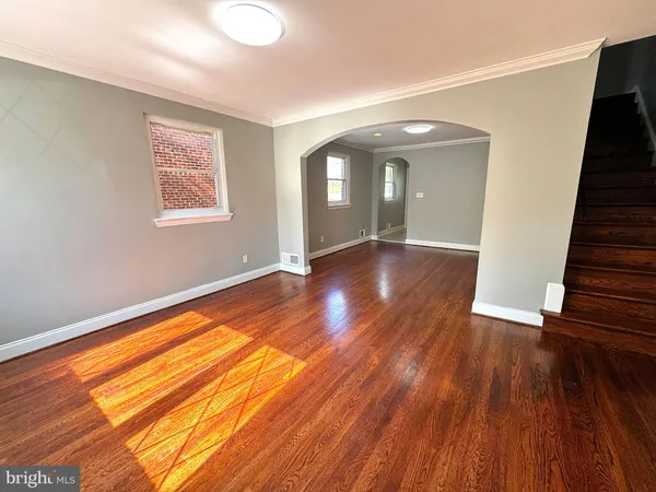 a view of an empty room with wooden floor and stairs