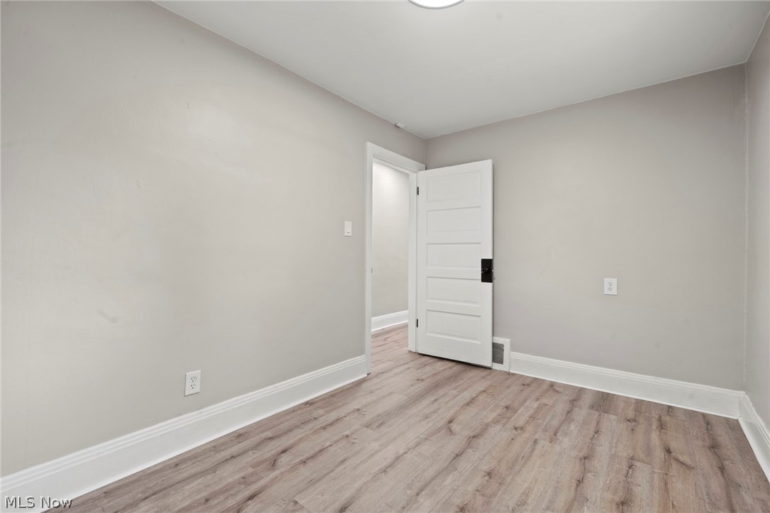 1218 Briggle Road Akron, OH 44320 - Photo 19 of 40 Room featuring light wood-finish flooring, white baseboards, light neutral wall paint, and a classic four-panel interior door with dark hardware