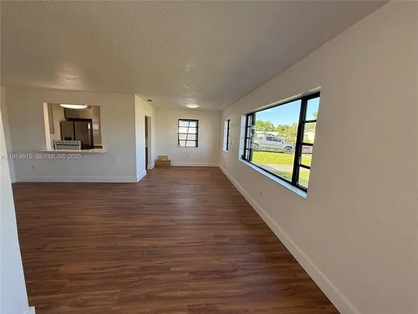 a view of an empty room with window and wooden floor