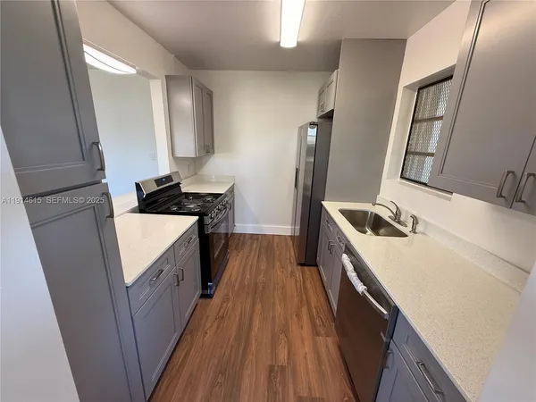 a kitchen with sink a refrigerator and wooden floor