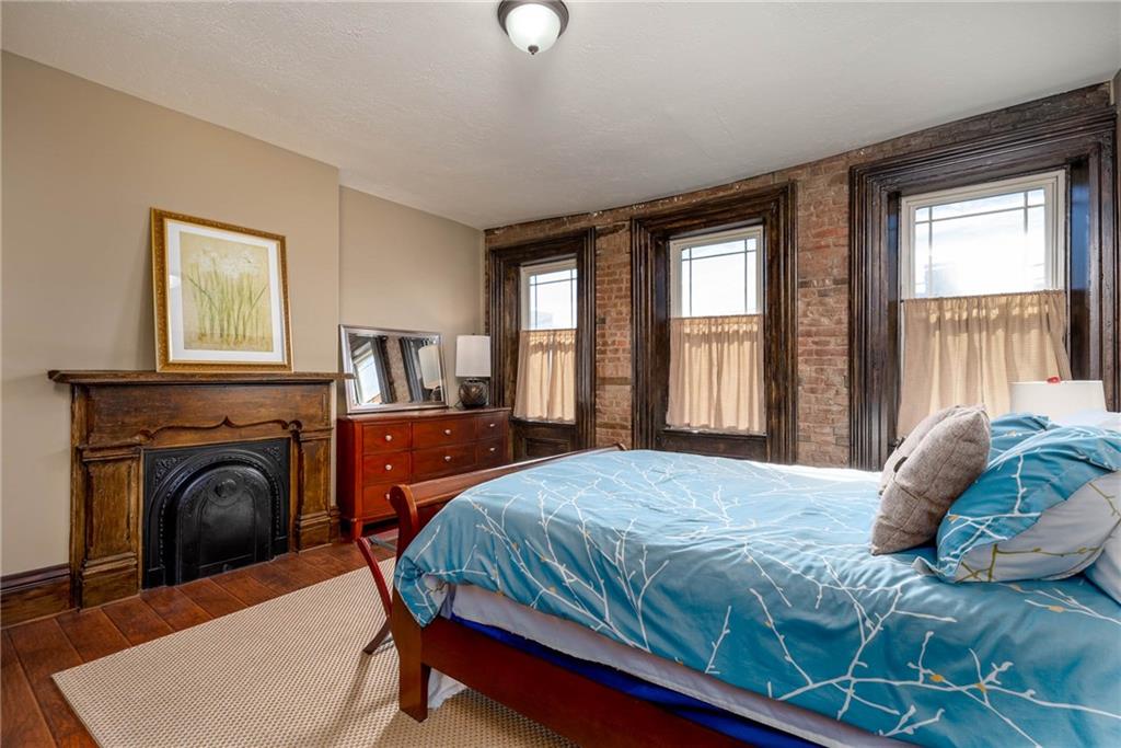 838 Spring Garden Avenue Pittsburgh, PA 15212 - Photo 16 of 24 a bedroom with a large bed a fireplace and windows