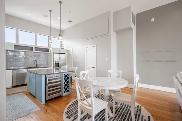 a kitchen with stainless steel appliances granite countertop a stove top oven a dining table and chairs with wooden floor