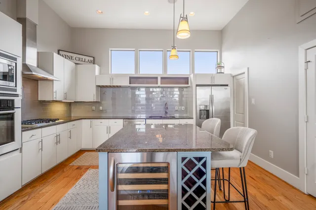 a view of a dining room and livingroom with furniture wooden floor kitchen chandelier