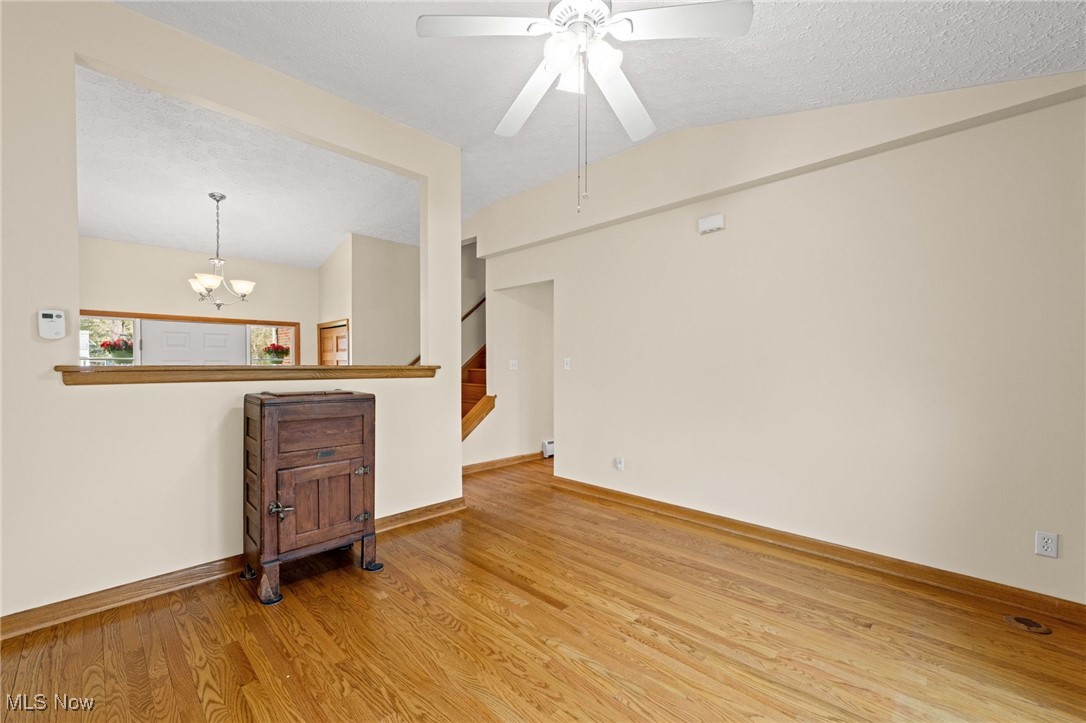 7590 Little Mountain Road Mentor, OH 44060 - Photo 10 of 40 Spare room with wood finished floors, ceiling fan with notable chandelier, baseboards, and lofted ceiling
