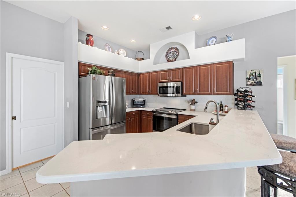 21516 Langholm Run Estero, FL 33928 - Photo 9 of 50 a kitchen with stainless steel appliances granite countertop a sink a stove a refrigerator and cabinets