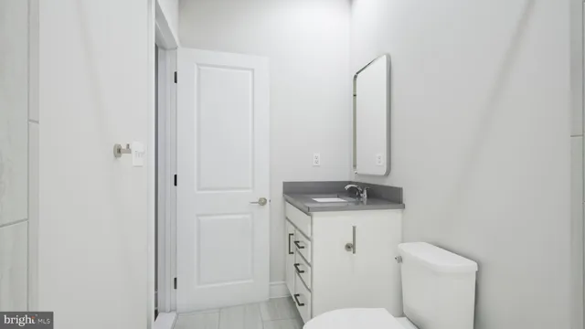 a bathroom with a granite countertop toilet sink and mirror