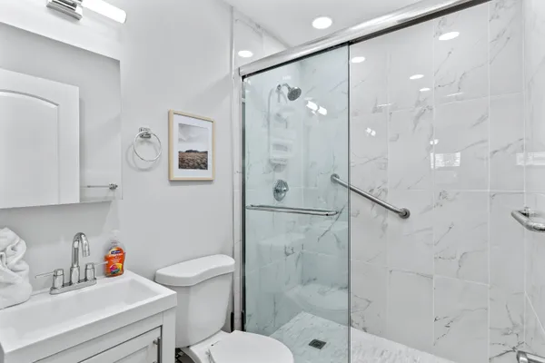 a bathroom with a shower sink vanity mirror and toilet