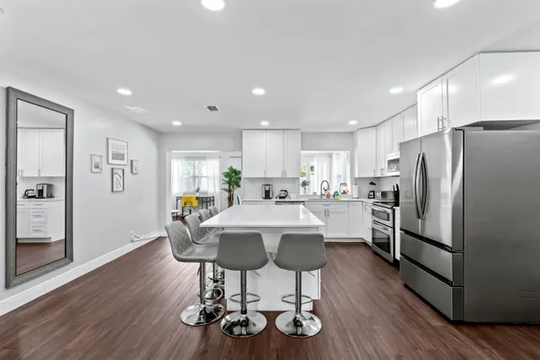 a kitchen with stainless steel appliances a dining table chairs refrigerator and cabinets