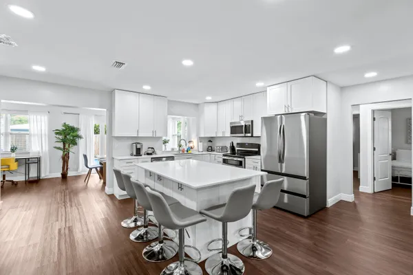a kitchen with stainless steel appliances a dining table chairs refrigerator and sink