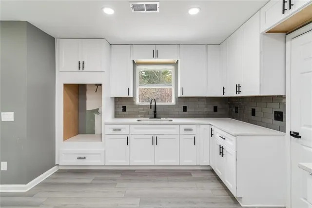a kitchen with white cabinets and sink