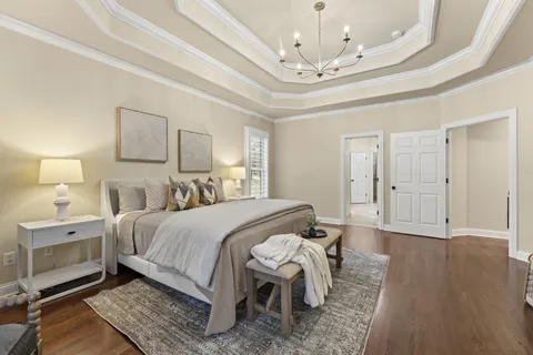 a spacious bedroom with a bed a chandelier and a window