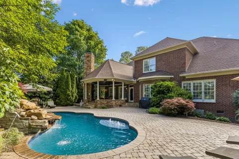 a view of a house with pool plants and chairs