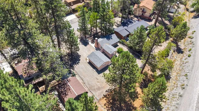 an aerial view of residential house with outdoor space and trees all around