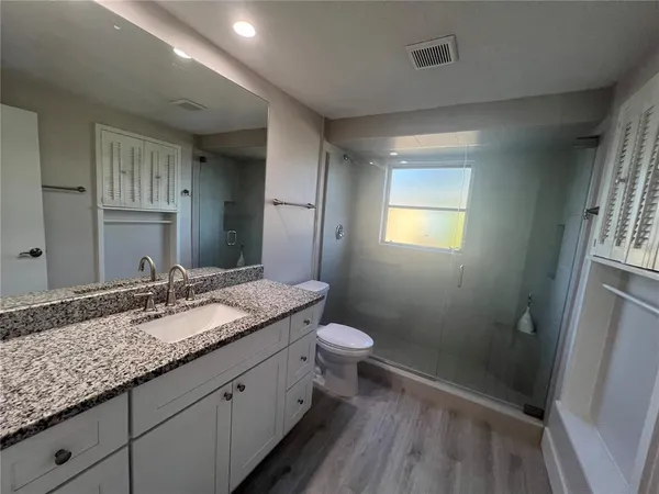 a bathroom with a granite countertop sink toilet and shower