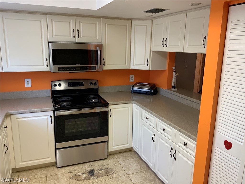 7055 New Post Road, Unit 5 North Fort Myers, FL 33917 - Photo 8 of 33 a kitchen with stainless steel appliances white cabinets a stove a sink and a microwave