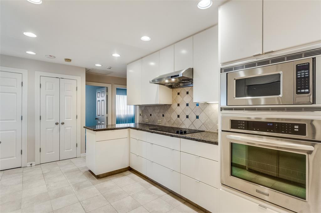 5200 Keller Springs Road, Unit 820 Dallas, TX 75248 - Photo 13 of 40 a kitchen with stainless steel appliances kitchen island granite countertop a stove and a sink