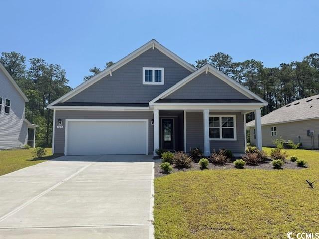 Craftsman house with covered porch, a front lawn, driveway, and a garage
